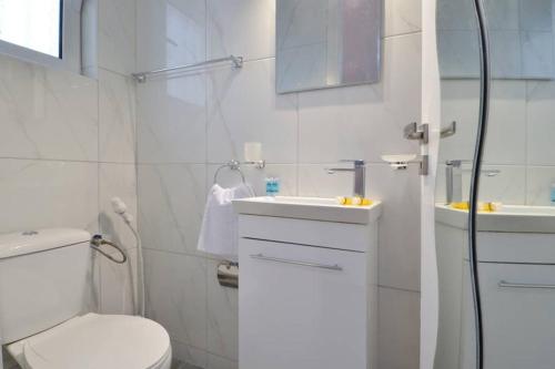a white bathroom with a toilet and a sink at Agia Paraskevi, a cozy and minimal retire in Athens