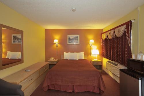 a hotel room with a bed and a mirror at Regency Inn in Winnemucca