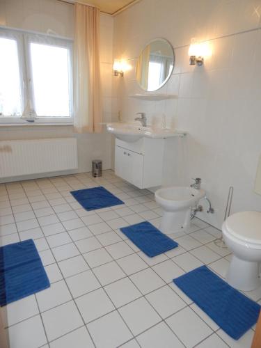 a bathroom with a toilet and a sink and blue mats at Ferienhaus "NordseeZeit" in Burhave