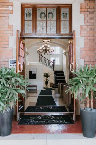a hallway of a building with a staircase and potted plants at Quality Hotel Regent Rockhampton in Rockhampton