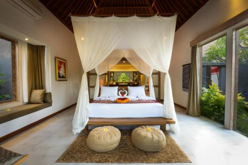 a bedroom with a bed with a canopy at Purana Boutique Resort in Ubud