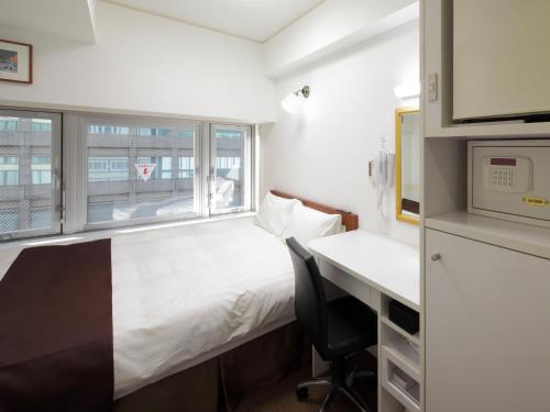 京都市にあるチェックイン四条烏丸のベッド、デスク、窓が備わる小さな客室です。