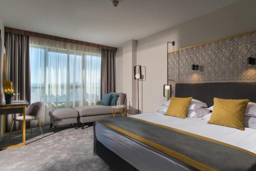 ein Hotelzimmer mit einem großen Bett und einem Schreibtisch in der Unterkunft Rosslyn Central Park Hotel Sofia in Sofia