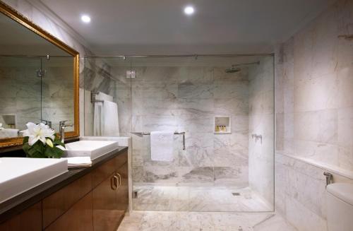 a bathroom with a shower and two sinks and a tub at The Sultan Residences Jakarta in Jakarta