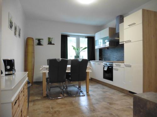 a kitchen with a table and two black chairs at Moerth Apartment in Schalchham