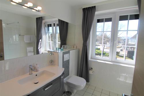 a bathroom with a sink and a toilet and a mirror at Landhotel garni zur Linde in Ratekau