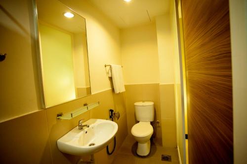 a bathroom with a sink and a toilet and a mirror at Mangga Boutique Hotel in Seri Kembangan