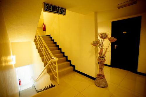 a hallway with a staircase and a vase with flowers at Mangga Boutique Hotel in Seri Kembangan