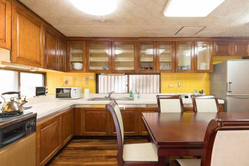 a kitchen with wooden cabinets and a wooden table with a dining room at NahaCentaral_10Beds7roomsHouse_190sqm_FreeParking in Naha