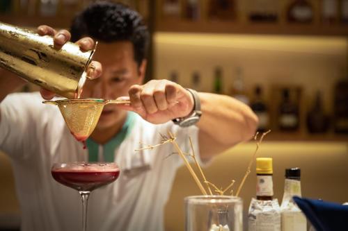 a man mixing a drink in a martini glass at Raffles Maldives Meradhoo in Gaafu Alifu Atoll
