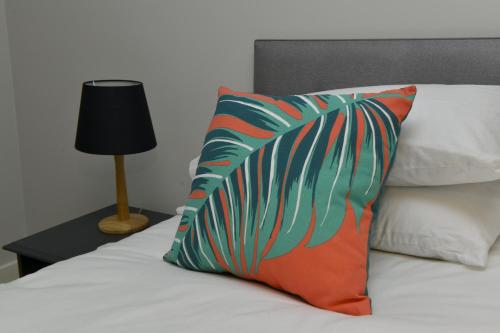 una almohada colorida sentada en una cama junto a una lámpara en 10A Ruston Chambers Free parking, Luxury 2 bedroom city center apartment en St Ives