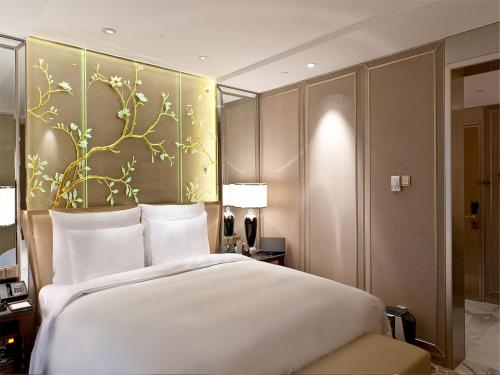 - une chambre avec un grand lit blanc et un mur fleuri dans l'établissement The Kunlun Beijing, à Pékin