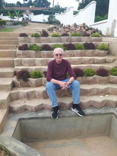a man sitting on a set of stairs at Kigezi Gardens Inn in Kabale