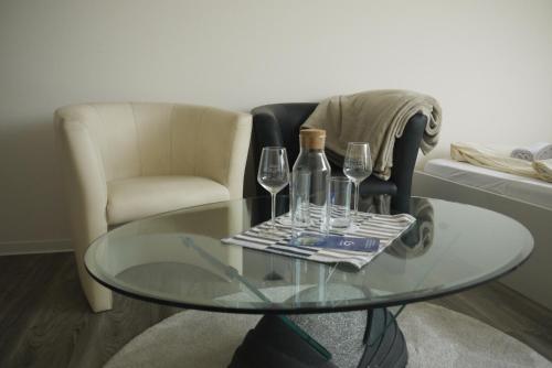 a glass table with wine glasses and a chair at Vermietung Flaßkamp in Harsewinkel
