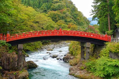 a red bridge over a river next to a stream at Chuzenji Pension in Nikko