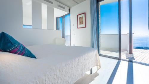 een witte slaapkamer met een bed en een groot raam bij Villa El Mirador in Begur
