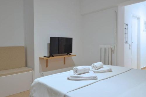 Habitación blanca con cama y TV en Acropolis, a nice and minimal apartment en Atenas