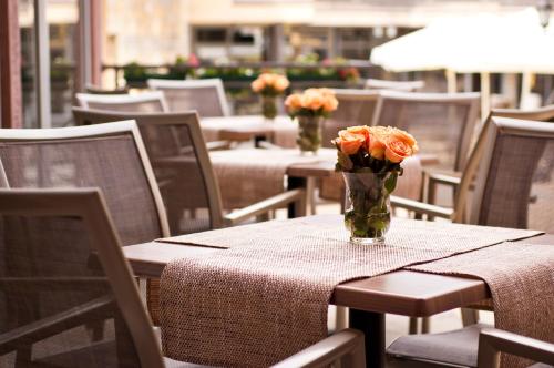 a vase of flowers sitting on a table with chairs at Hill Hotel Wellness & Spa in Jagodina
