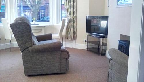 a living room with two chairs and a television at Columbus Holiday Flats in Scarborough