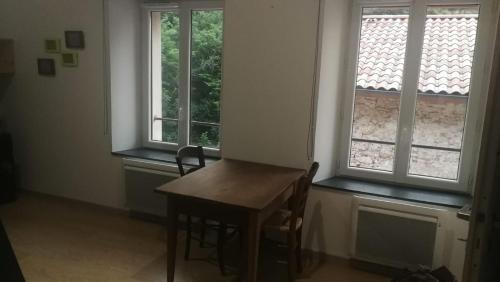 a room with a wooden table and two windows at Gîte au coeur du parc naturel régional du Pilat in Pélussin