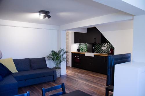 a living room with a blue couch and a kitchen at Dorpsplein Appartement in Zandvoort