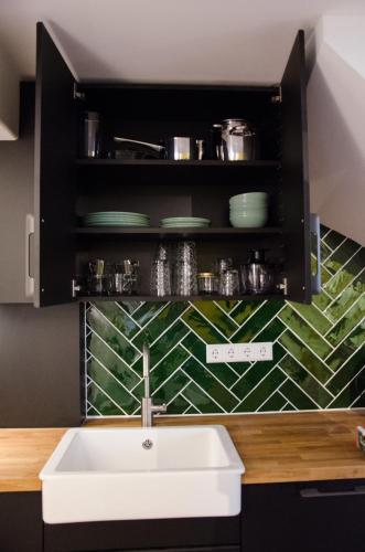 a kitchen with a sink and a shelf with dishes at Dorpsplein Appartement in Zandvoort