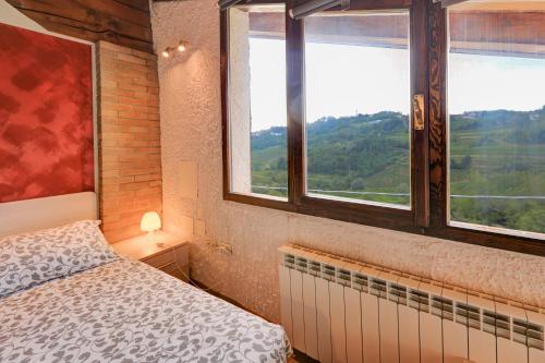 a bedroom with a bed and windows with a view at Dal Rosso in San Floriano del Cóllio