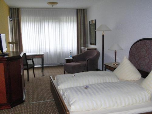 a hotel room with a bed and a chair at Hotel Moselkern in Moselkern