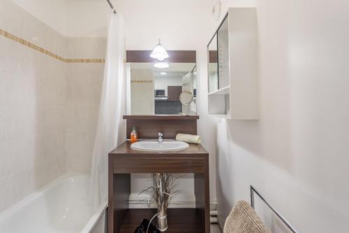 une salle de bain avec un lavabo, un miroir et une baignoire dans l'établissement Appartement Confort Paris, à Montévrain