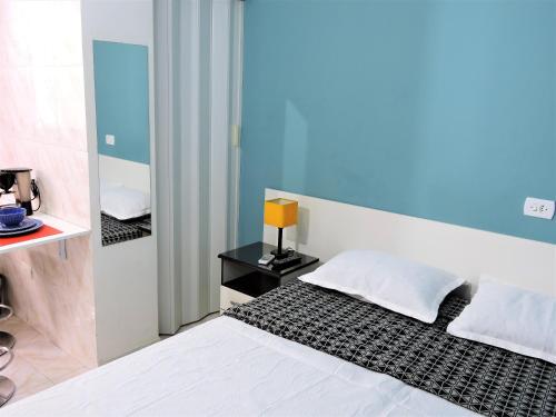 a bedroom with a white bed and a mirror at 10 Studios in Sao Paulo