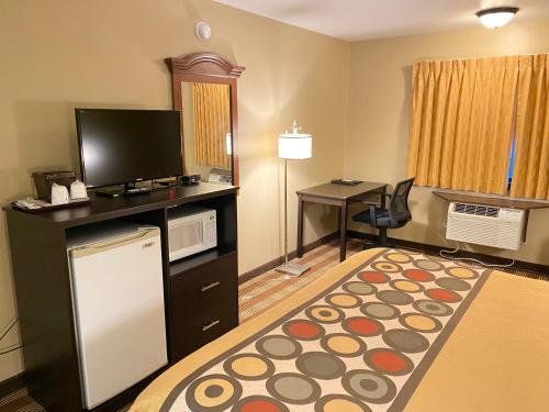 a hotel room with a television and a desk with a table at Super 8 by Wyndham Eau Claire WI in Eau Claire