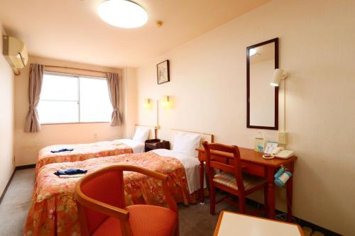 una camera d'albergo con 2 letti, una scrivania e uno specchio di Business Hotel Miharashitei a Kumano