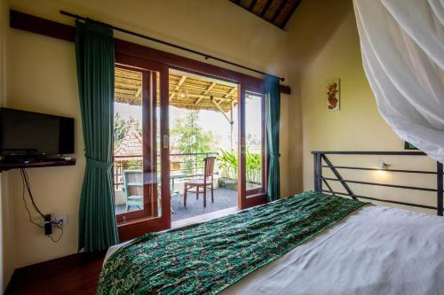 Schlafzimmer mit einem Bett und Blick auf einen Balkon in der Unterkunft Sisin Ubud View in Ubud