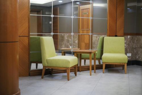 a waiting room with green chairs and a table at Classic Hotel in Muar