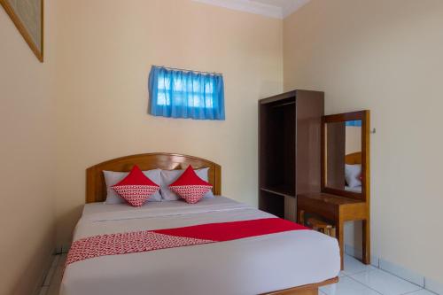 a bedroom with a bed with red pillows and a mirror at SUPER OYO 3024 Hotel Kebon Manis in Cilacap