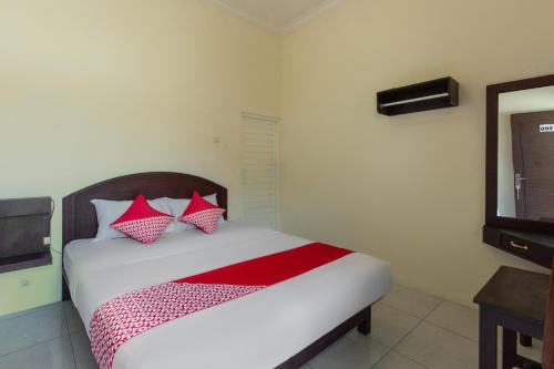 a bedroom with a bed with red and white pillows at SUPER OYO 3024 Hotel Kebon Manis in Cilacap