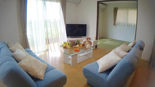 a living room with a blue couch and a tv at Ecot Shimozato 1 in Miyako-jima