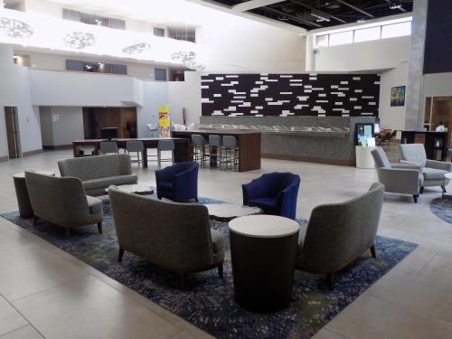 a waiting area with chairs and tables and a lobby at Holiday Inn Orlando International Airport by IHG in Orlando