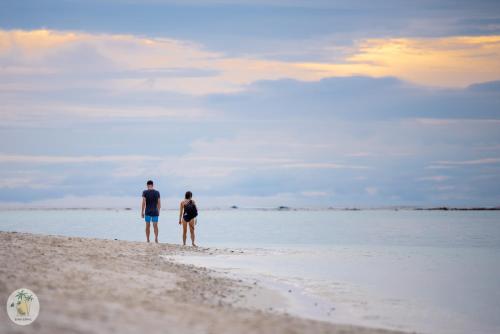 a man and a woman standing on the beach at Shifa Lodge Maldives in Feridhoo