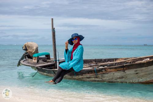 a woman sitting on a boat on the beach at Shifa Lodge Maldives in Feridhoo