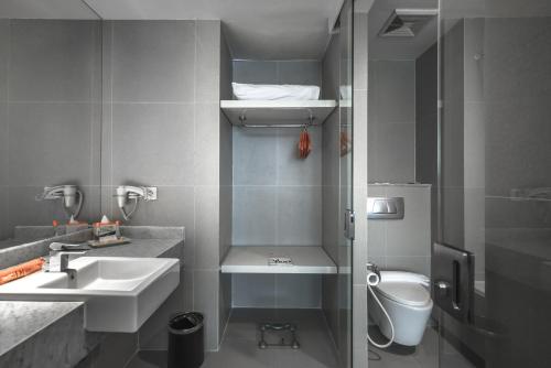 ein kleines Bad mit einem Waschbecken und einem WC in der Unterkunft HARRIS Hotel & Conventions Malang in Malang