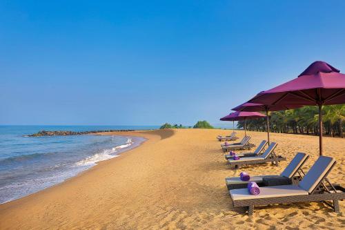 a row of lounge chairs and umbrellas on a beach at Avani Kalutara Resort in Kalutara