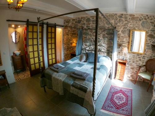 a bedroom with a bed and a stone wall at Chez les Amis in Saint-Nazaire-de-Ladarez