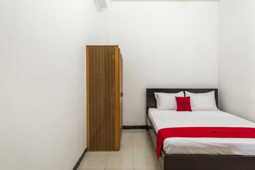 RedDoorz near Widya Mandala University في سورابايا: غرفة نوم بسريرين ومخدة حمراء