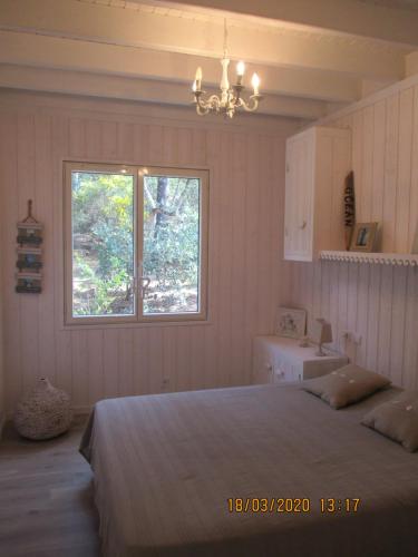 1 dormitorio con cama, ventana y lavamanos en une maison lumineuse sous les pins en Le Canon