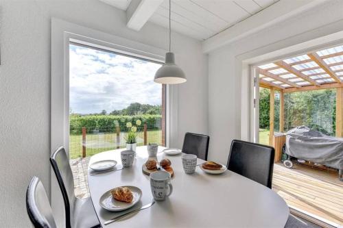 a white dining room with a table and a large window at Thatched Holiday Home in Struer, Jutland with a view in Struer