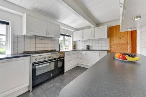 a kitchen with white appliances and a bowl of fruit on a counter at Thatched Holiday Home in Struer, Jutland with a view in Struer
