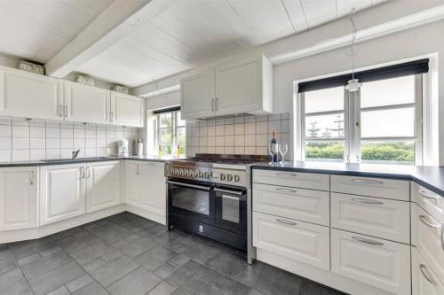 a kitchen with white cabinets and a stove top oven at Thatched Holiday Home in Struer, Jutland with a view in Struer