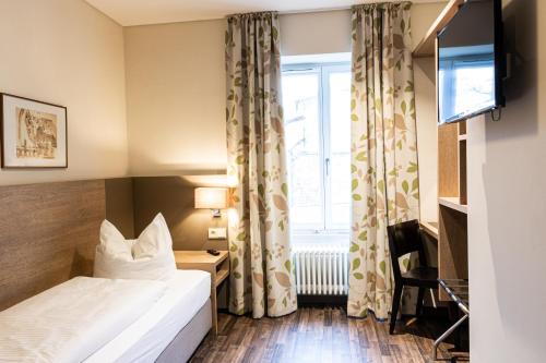una camera d'albergo con letto e finestra di Brauereigaststatte Spitalgarten a Ratisbona