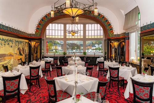restauracja z białymi stołami i krzesłami oraz żyrandolem w obiekcie Romantik Jugendstilhotel Bellevue w mieście Traben-Trarbach